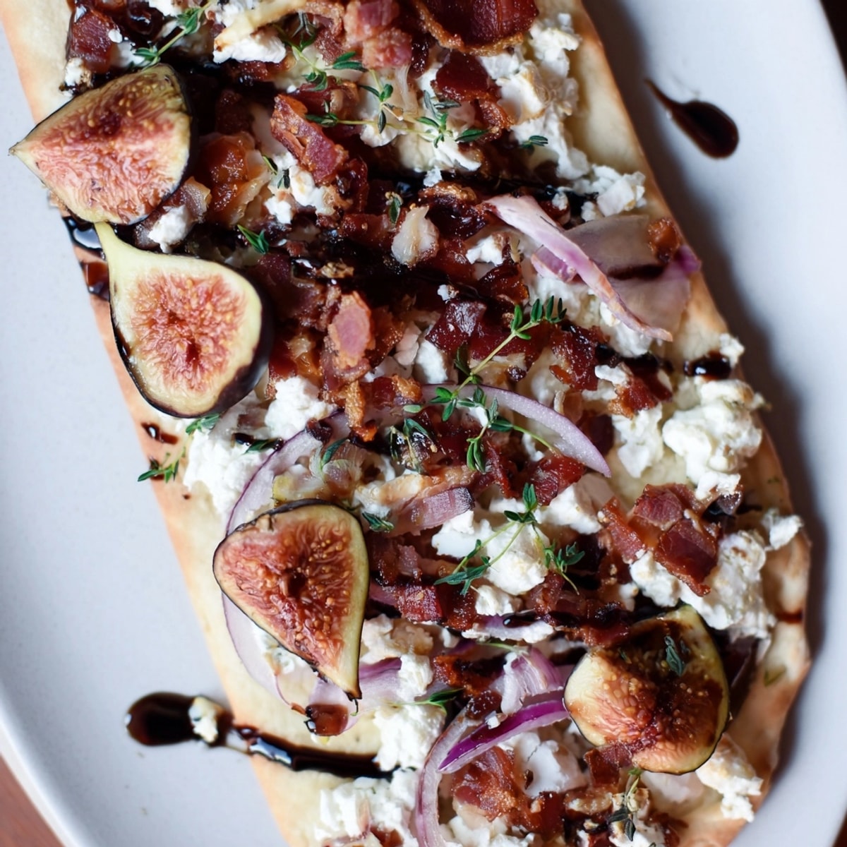 Overhead shot of golden Roasted Balsamic Fig & Bacon Flatbread with melting cheese.
