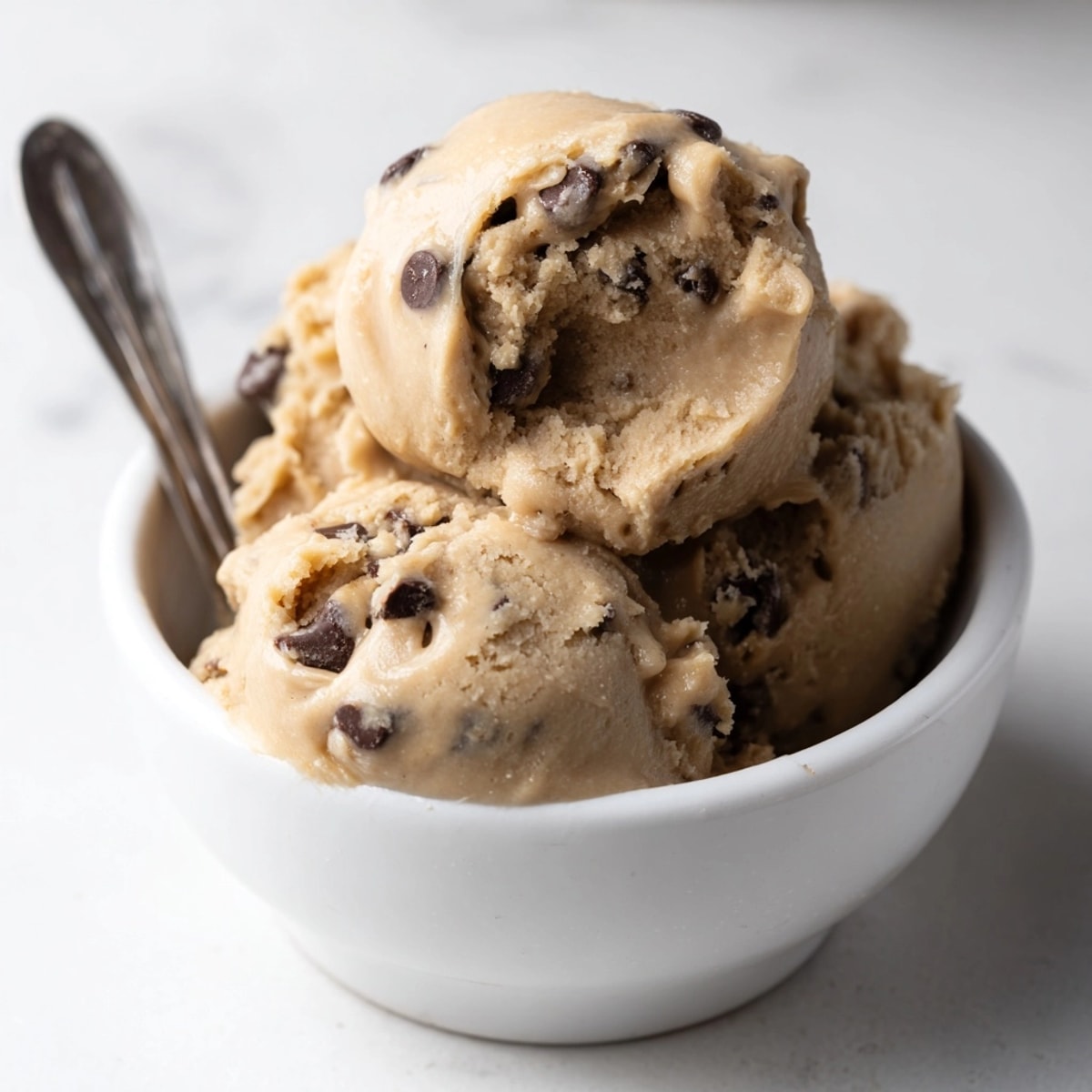Scoops of creamy, chocolate chip-studded edible cookie dough, ready for immediate, spoon-licking enjoyment.