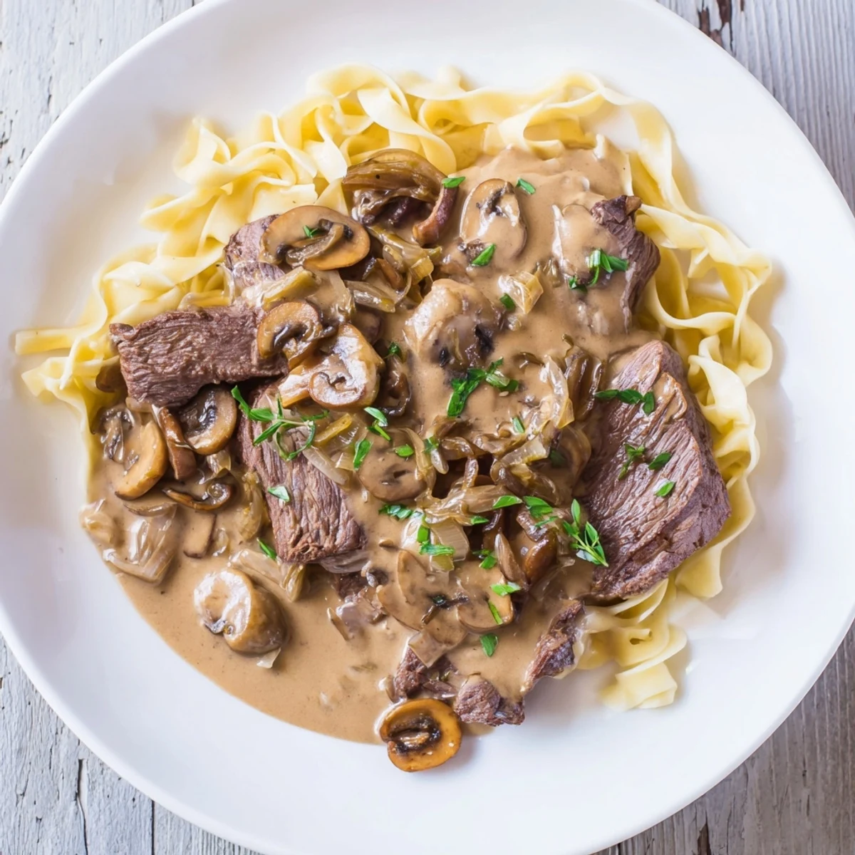 Close-up of beef stroganoff, with juicy beef strips and mushrooms, glistening in a savory sauce.