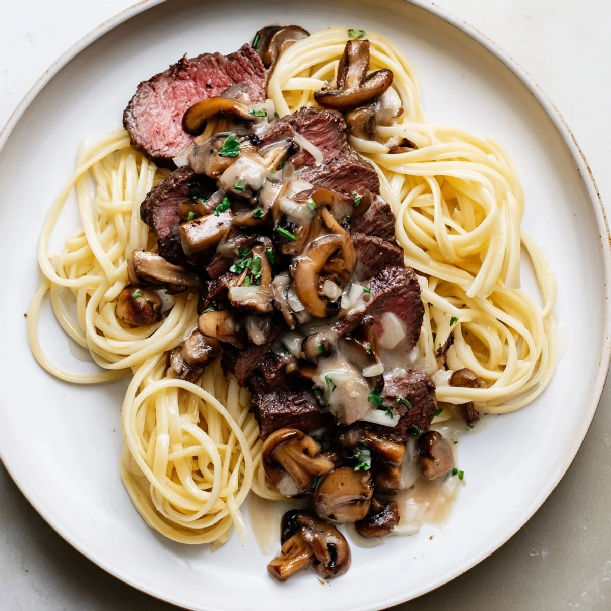 A steaming bowl of beef stroganoff, with rich, brown gravy over fluffy egg noodles, ready to eat.
