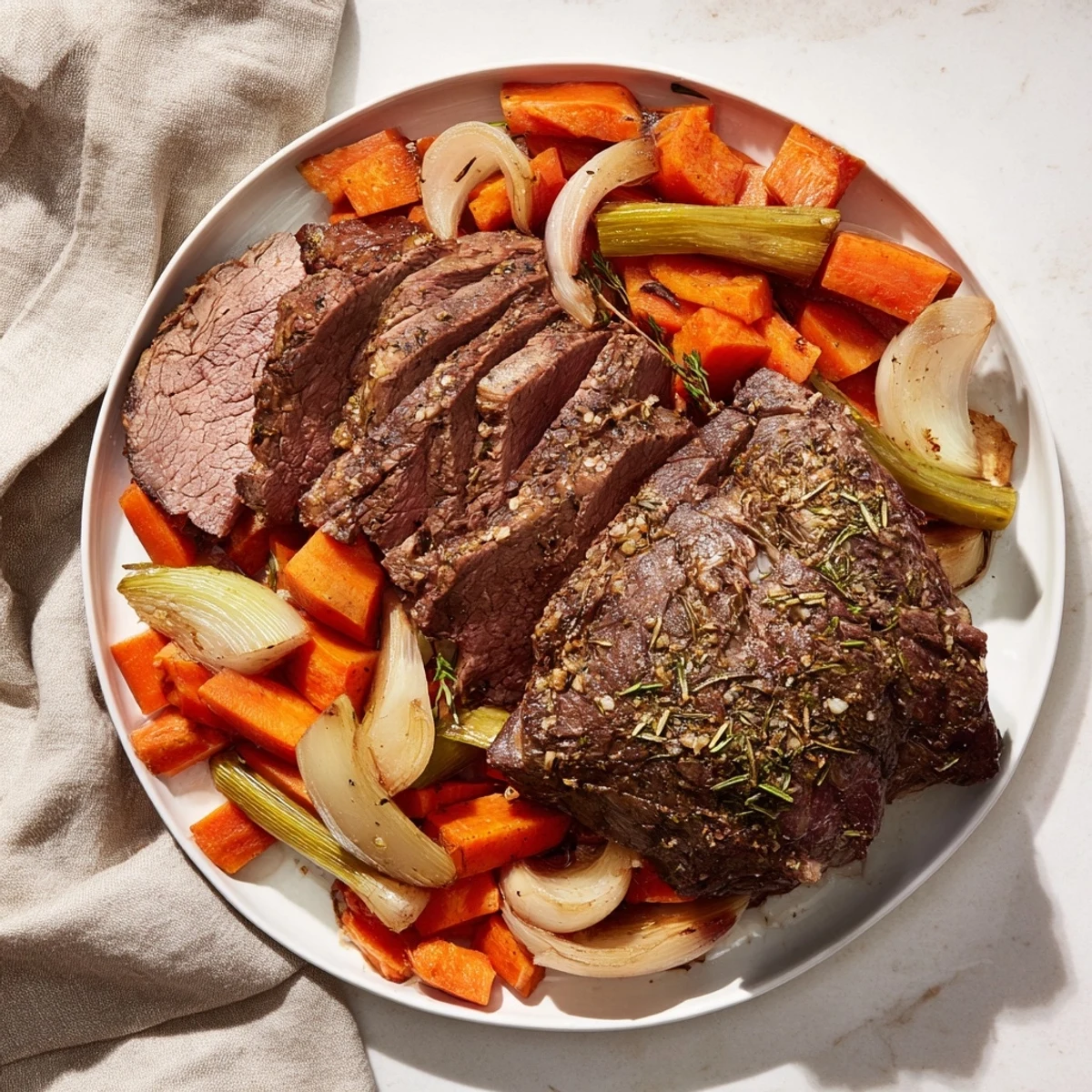 Juicy slow roasted beef, perfectly browned, accompanied by roasted carrots and onions in a flavorful pan sauce.