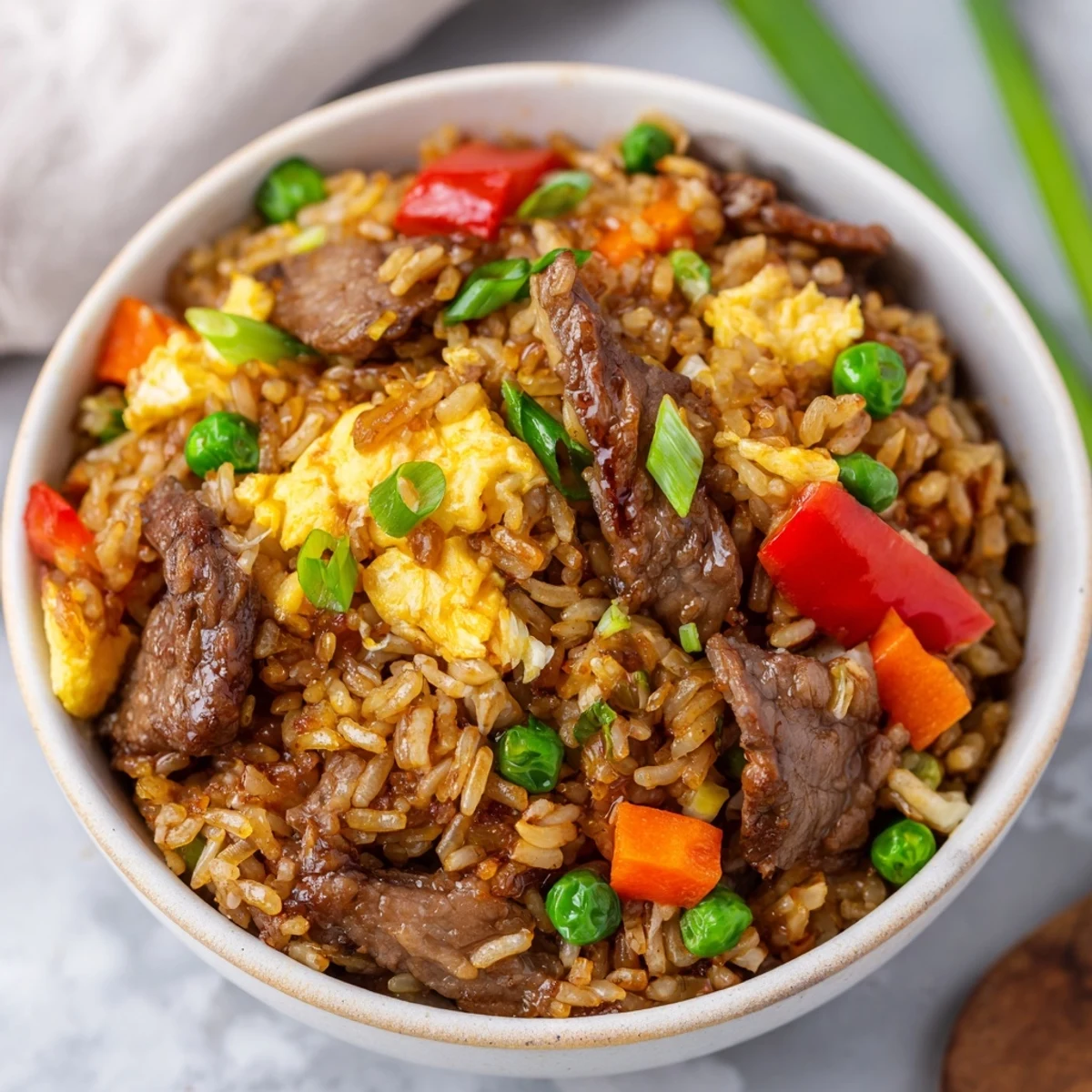 Steamed white rice is tossed with tender beef strips, vibrant peas, diced carrots, and fluffy scrambled eggs.