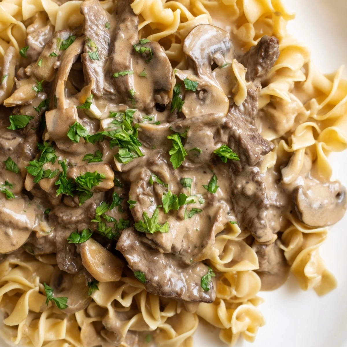 Hearty Beef and Mushroom Stroganoff simmering in a rich, tangy cream sauce, ready to be spooned over a bed of buttery egg noodles.