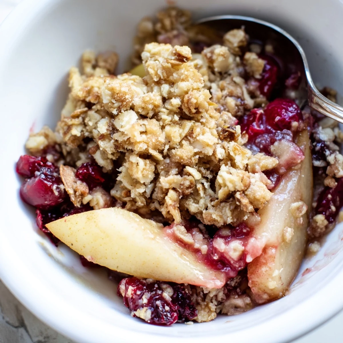 A close-up of golden Spiced Pear and Cranberry Crumble bubbling with cinnamon-spiced fruit.