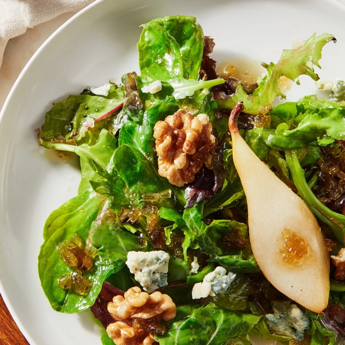 Freshly sliced pears and glossy candied walnuts top a bowl of crisp winter greens in this Winter Green Salad with Pear and Candied Walnuts, tossed in tangy vinaigrette.