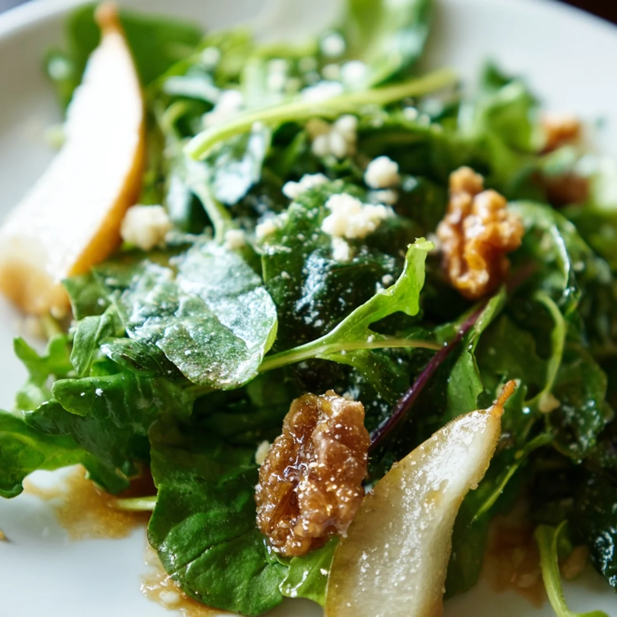A large serving bowl of Winter Green Salad with Pear and Candied Walnuts tossed with bright greens, dressed in a honey-Dijon vinaigrette for a fresh side dish.
