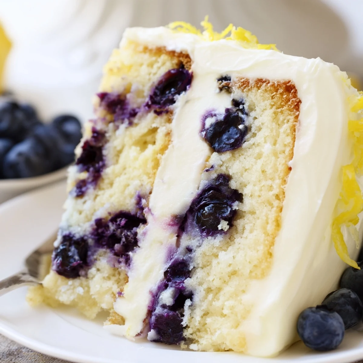 Vibrant Lemon Blueberry Cake with cream cheese frosting and lemon zest garnish, perfect for spring dessert tables and sweet cravings.
