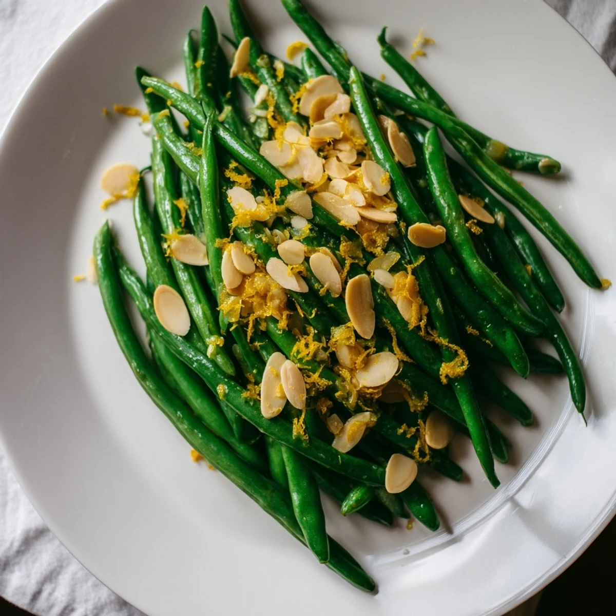 A skillet of green beans with lemon and almonds, finished with fresh juice and crunchy nuts.
