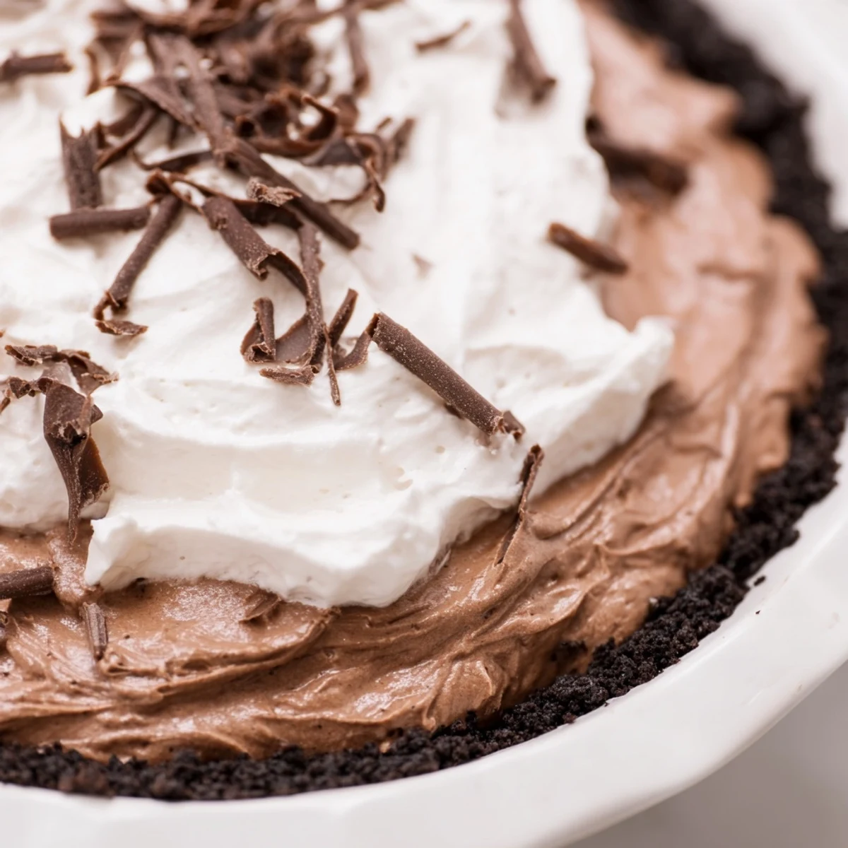 A slice of Romantic Chocolate Silk Pie with whipped cream topping on a dessert plate.