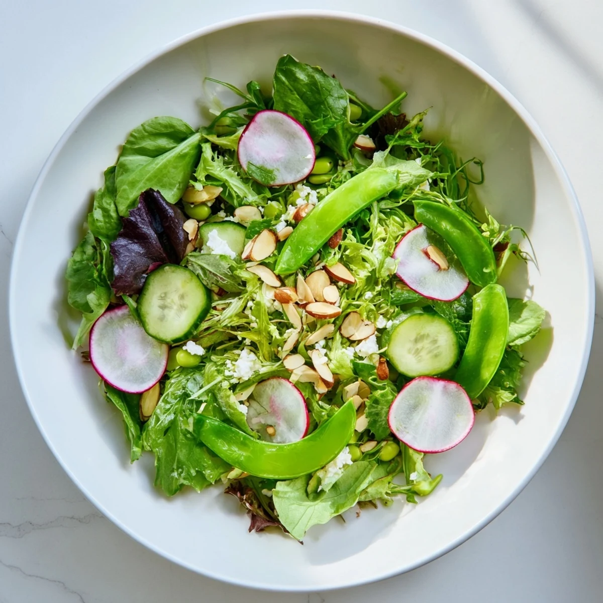 Spring Greens Salad with Lemon Vinaigrette showcases crisp greens, snap peas, and radishes, lightly dressed and topped with almonds.
