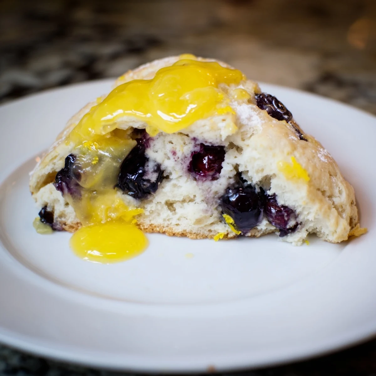 Freshly baked Lemon Blueberry Scones with Lemon Curd, golden and flaky, topped with a drizzle of glaze on a rustic wooden board.