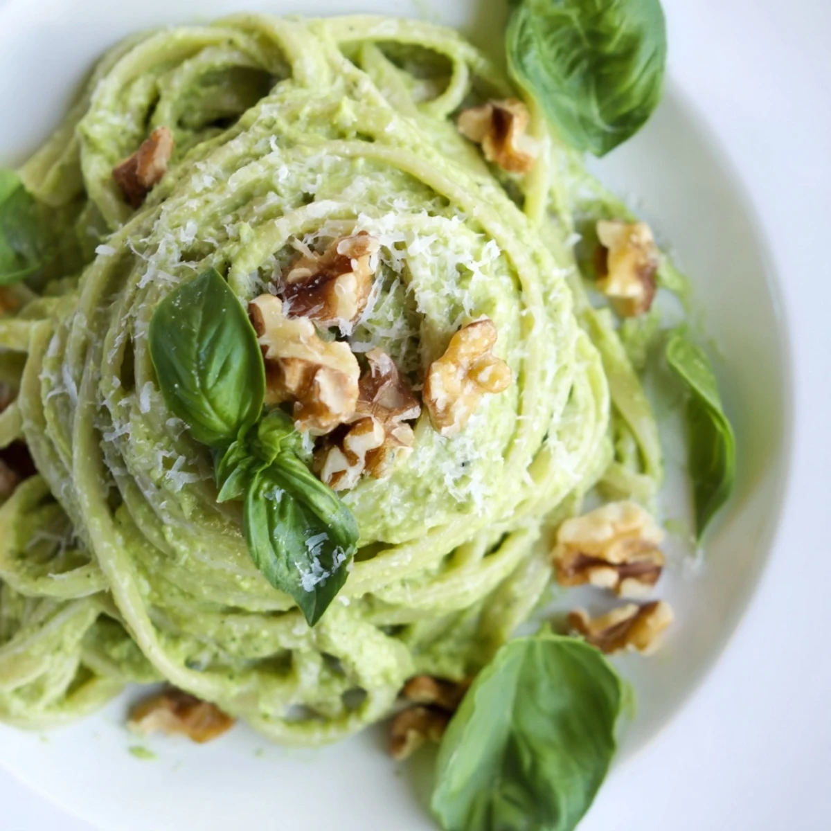 A close-up of Creamy Avocado and Spinach Pasta with Walnuts highlighting its vibrant green sauce and crunchy topping.