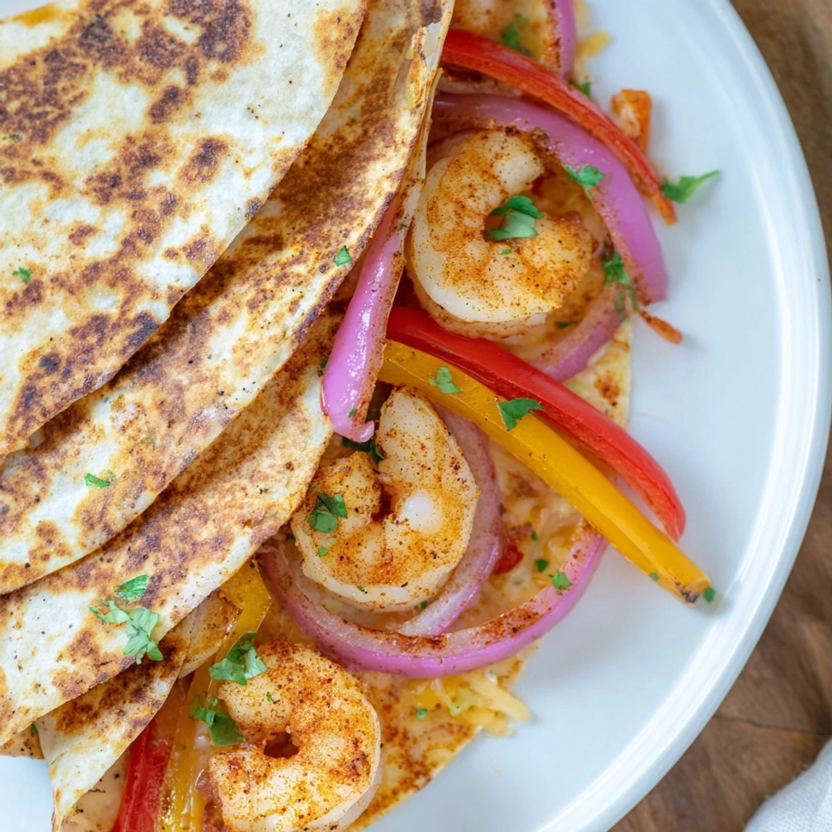 Close-up of a slice of Shrimp Fajita Sheet Pan Quesadillas revealing melted cheese, sautéed vegetables, and seasoned shrimp on a ceramic plate.