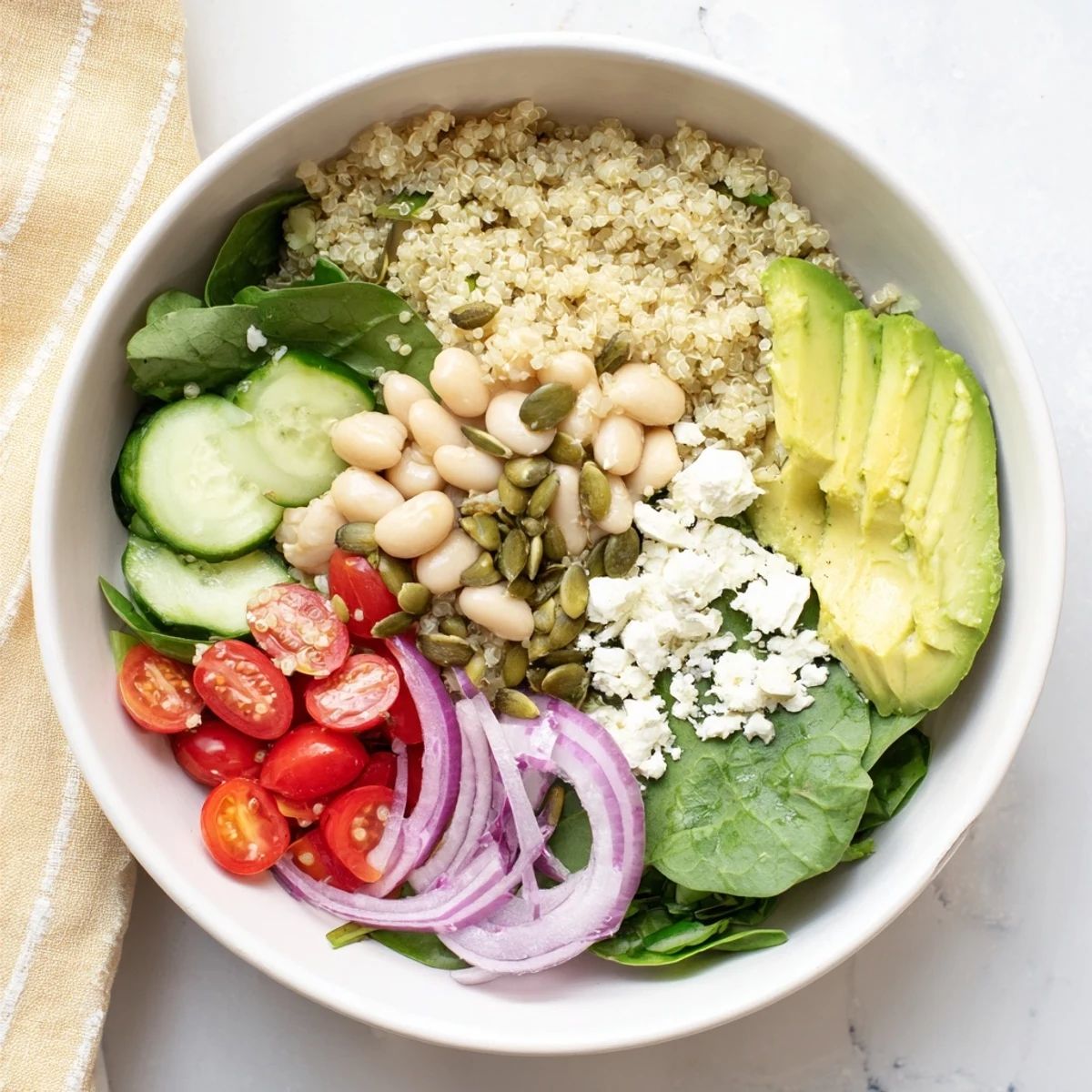 The completed Spinach & White Bean Ultimate Protein Power Bowl shows a tangy lemon-tahini dressing drizzled over colorful vegetables, feta, and seeds, presented for a nourishing lunch.
