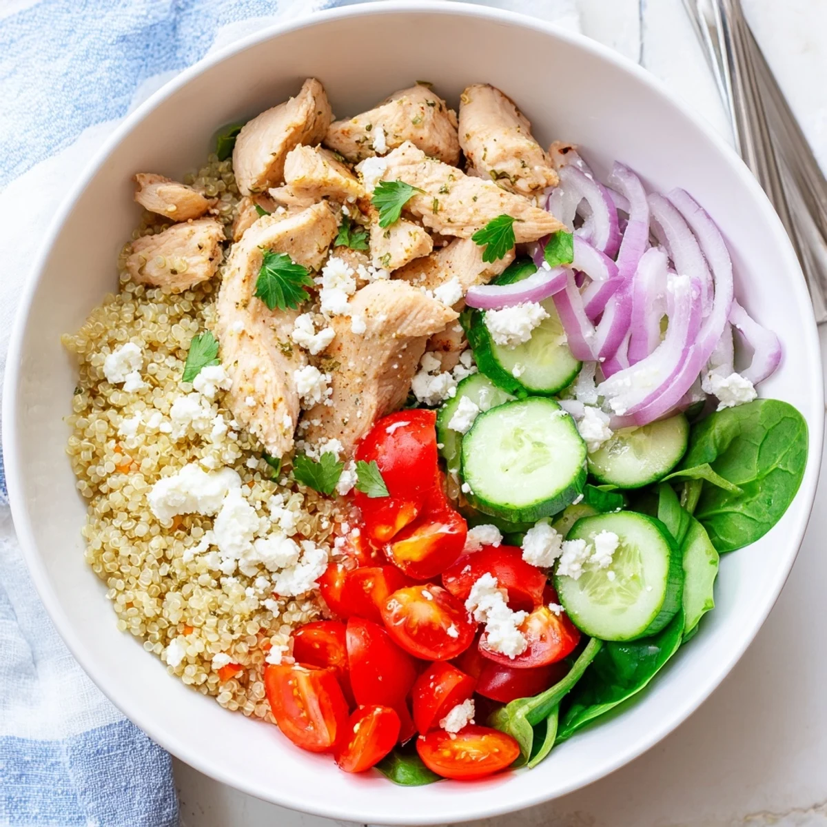 Vibrant bowl of Easy High-Protein Chicken & Quinoa Bowl with grilled chicken slices, fluffy quinoa, spinach, cherry tomatoes, cucumber, red bell pepper, and crumbled feta cheese, all drizzled with lemon-herb dressing on a rustic wooden table.