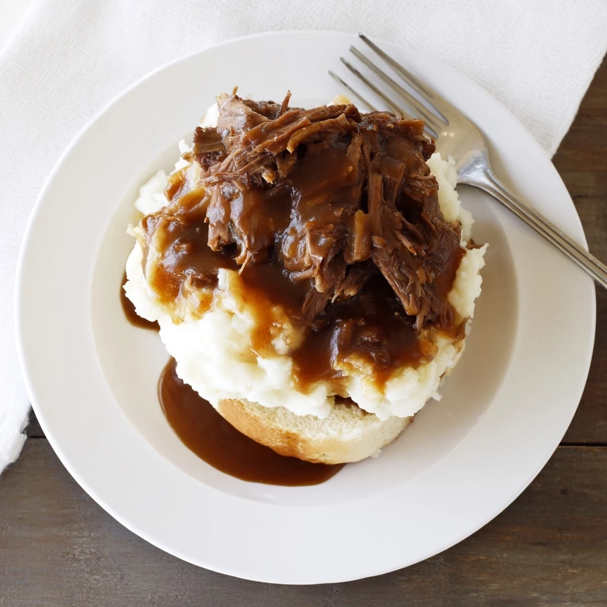 Shredded Slow Cooker Beef Manhattan piled on thick white bread with creamy mashed potatoes and rich brown gravy.