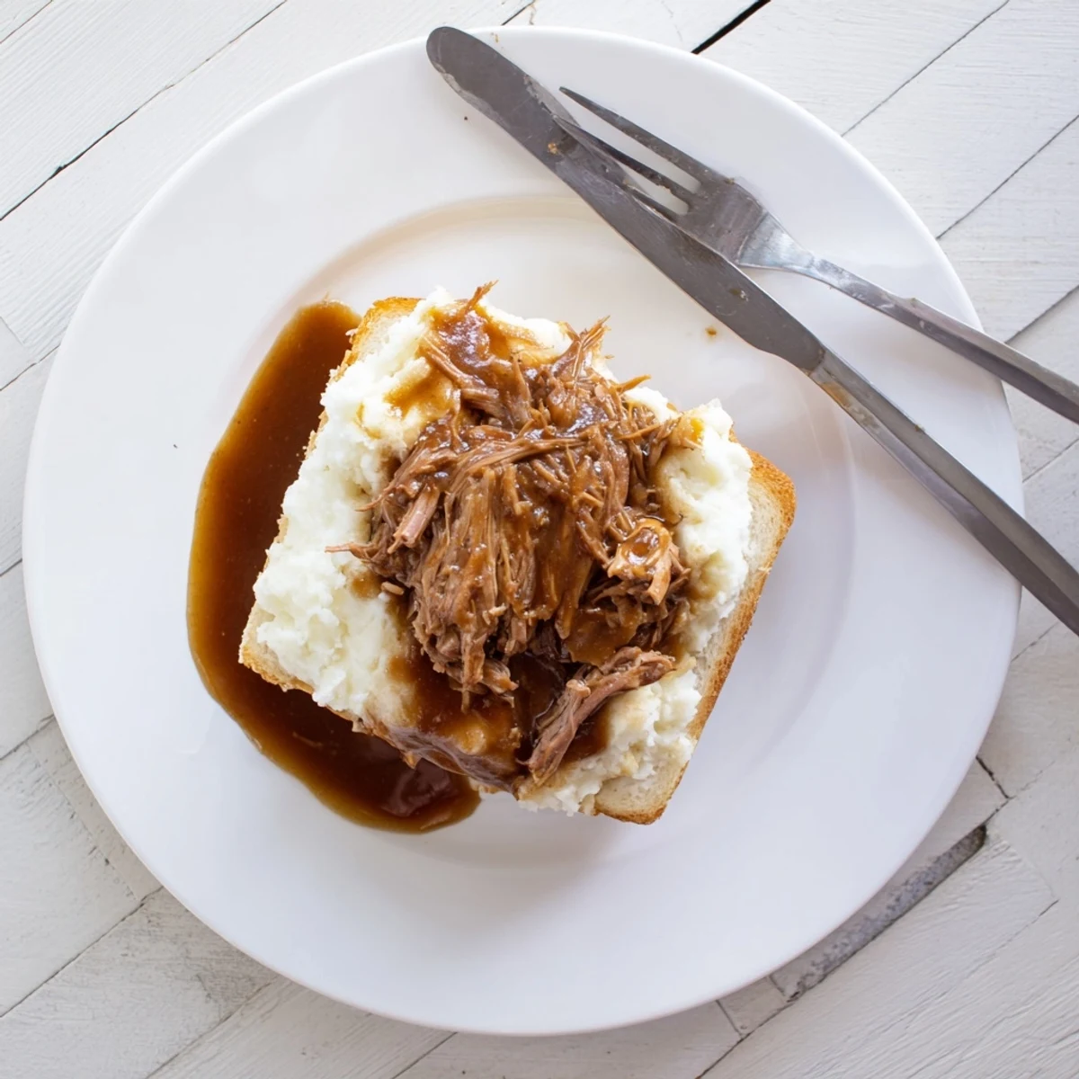 A comforting Midwestern dinner featuring tender Slow Cooker Beef Manhattan topped with buttery mashed potatoes and savory gravy.