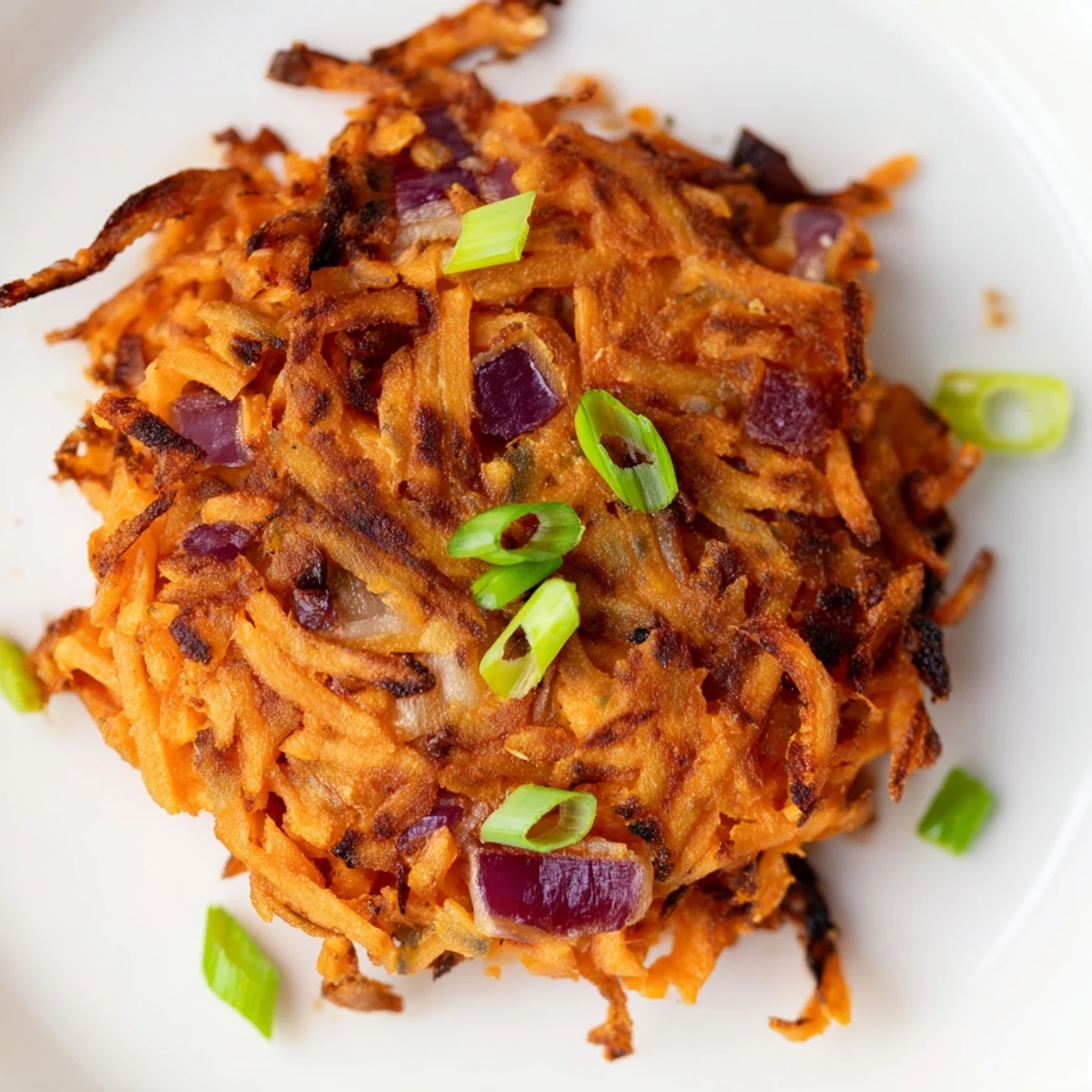Healthy Sweet Potato Hash Browns arranged on a rustic plate with vibrant spring onion garnish and a side of hot sauce.
