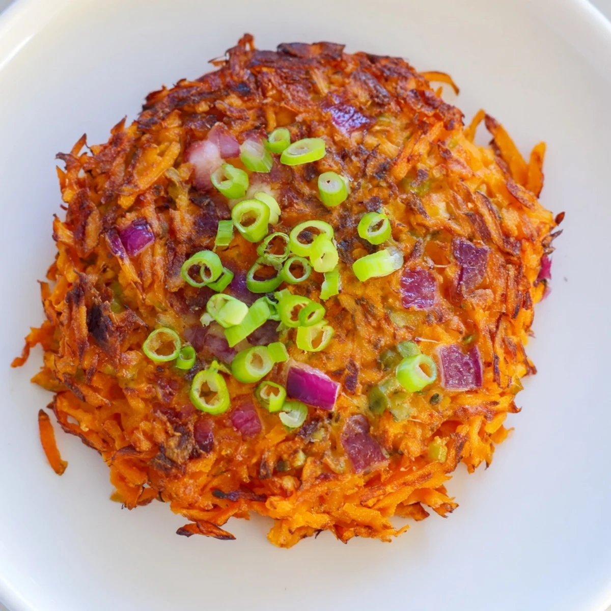 A close-up of Healthy Sweet Potato Hash Browns served with creamy avocado slices and a dollop of Greek yogurt for a savory breakfast.