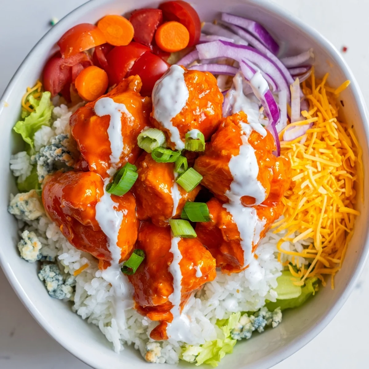 Zesty buffalo chicken and crisp romaine lettuce in a bowl, garnished with crunchy vegetables and a drizzle of cool, creamy ranch sauce.
