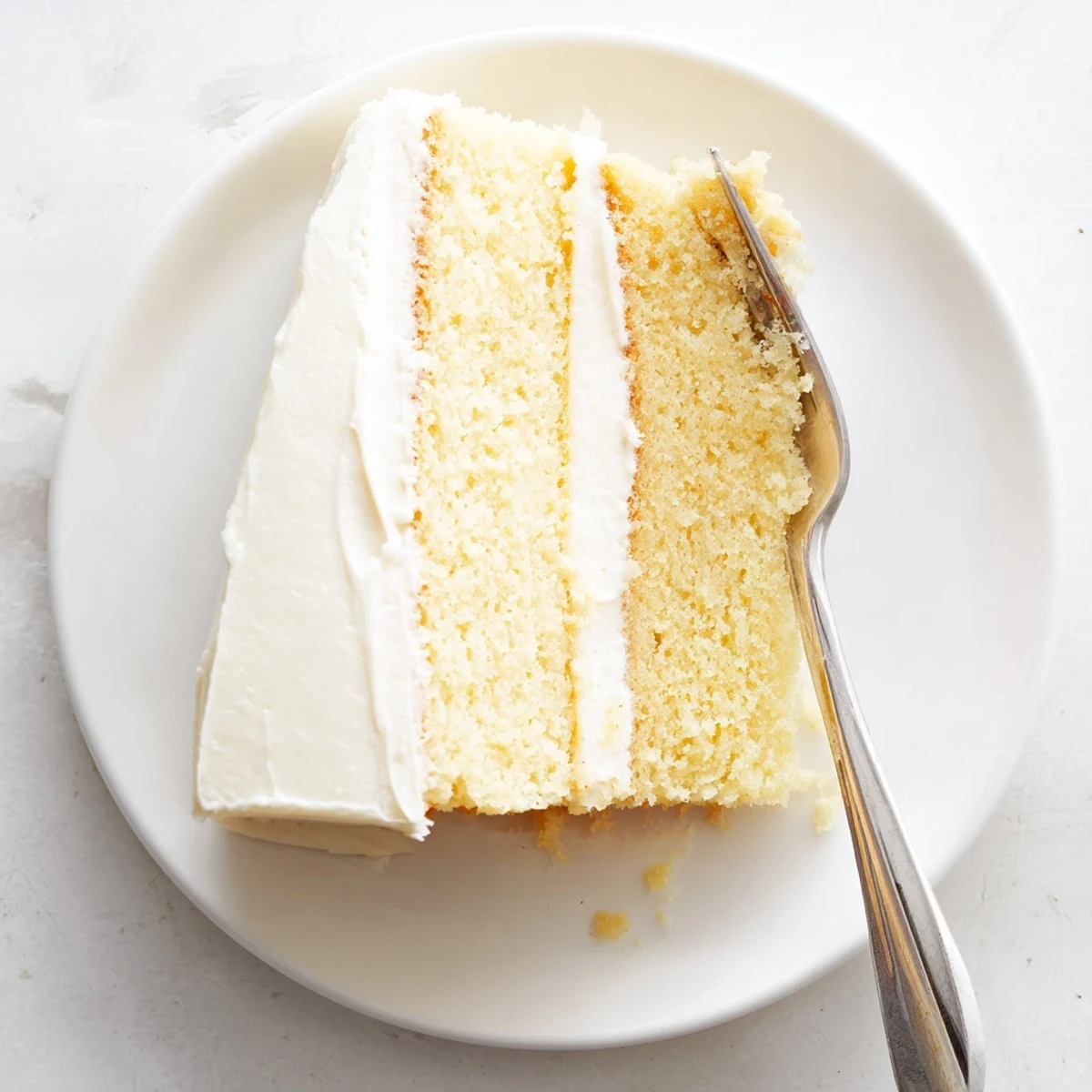 A slice of Perfect Vanilla Cake with creamy buttercream frosting and a soft crumb.