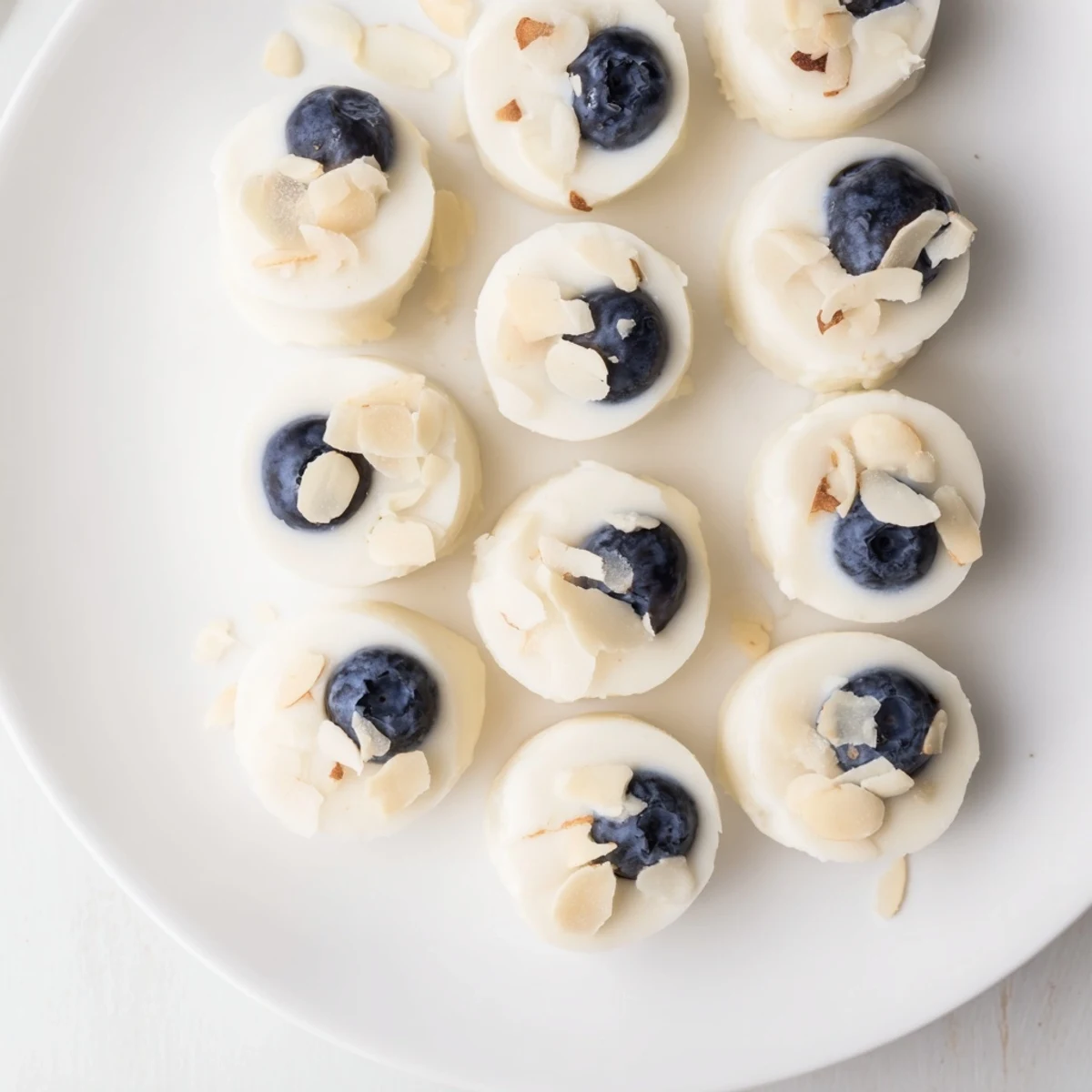 Freshly frozen Blueberry Greek Yogurt Bites topped with shredded coconut on a rustic wooden board.
