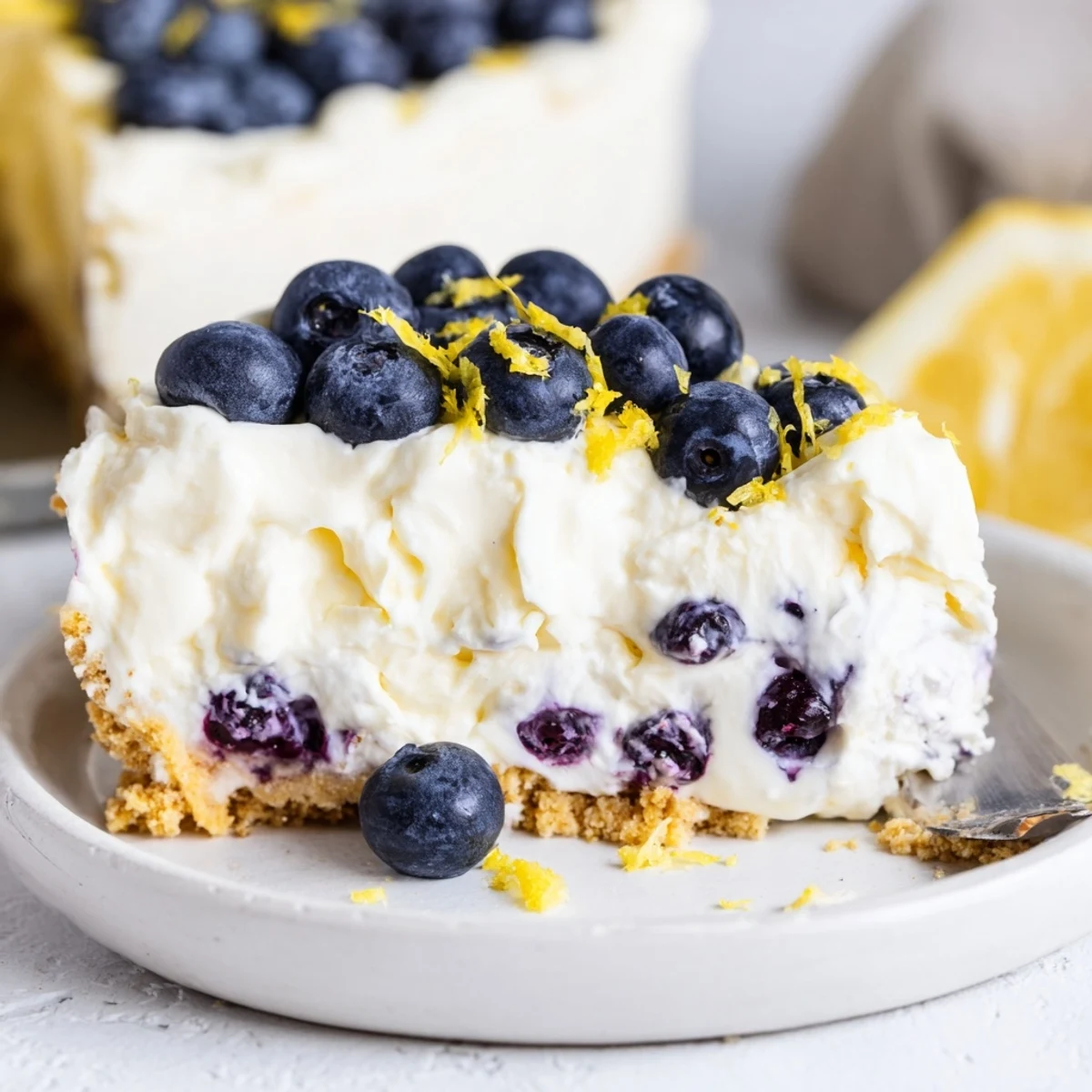 No Bake Lemon Blueberry Cream Cake with fresh blueberries and lemon zest on top, perfect for summer parties.  