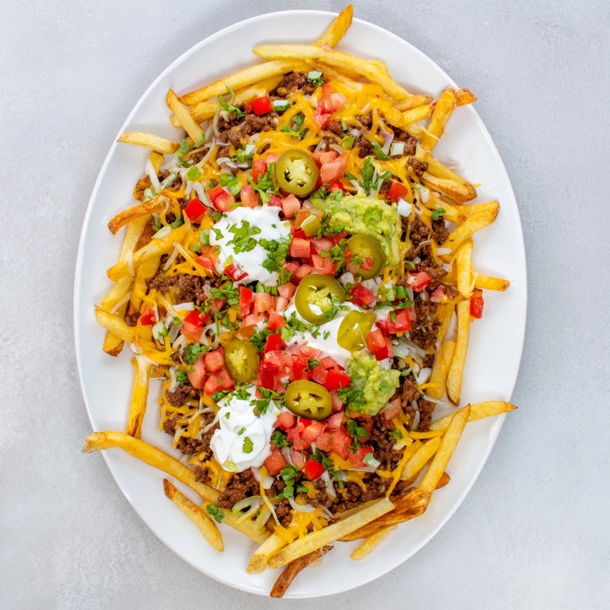 Sizzling taco beef loaded fries piled with savory meat, melty cheese blend, sour cream, and green onions