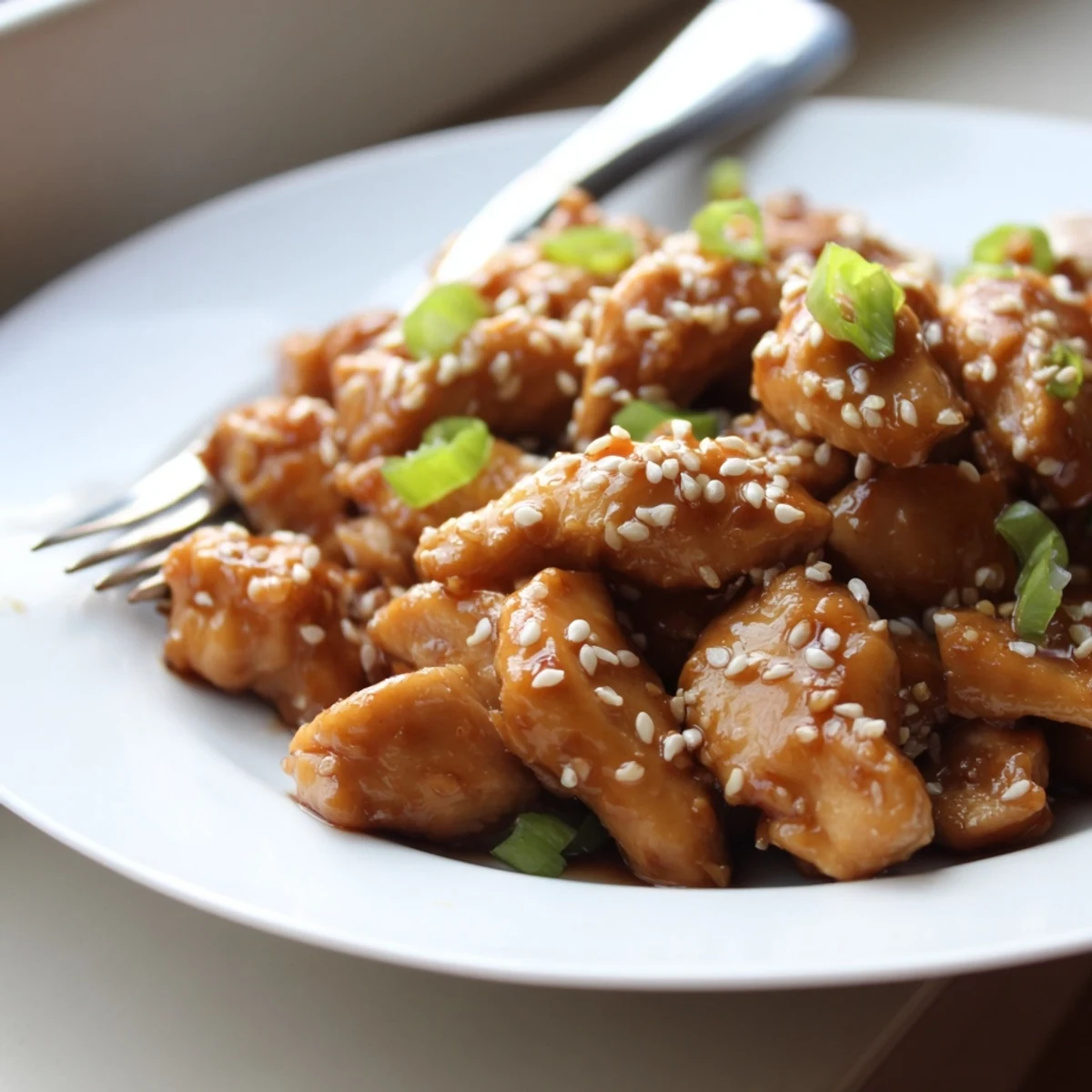 Golden pieces of Crock Pot Sesame Chicken coated in glossy sauce and sprinkled with sesame seeds