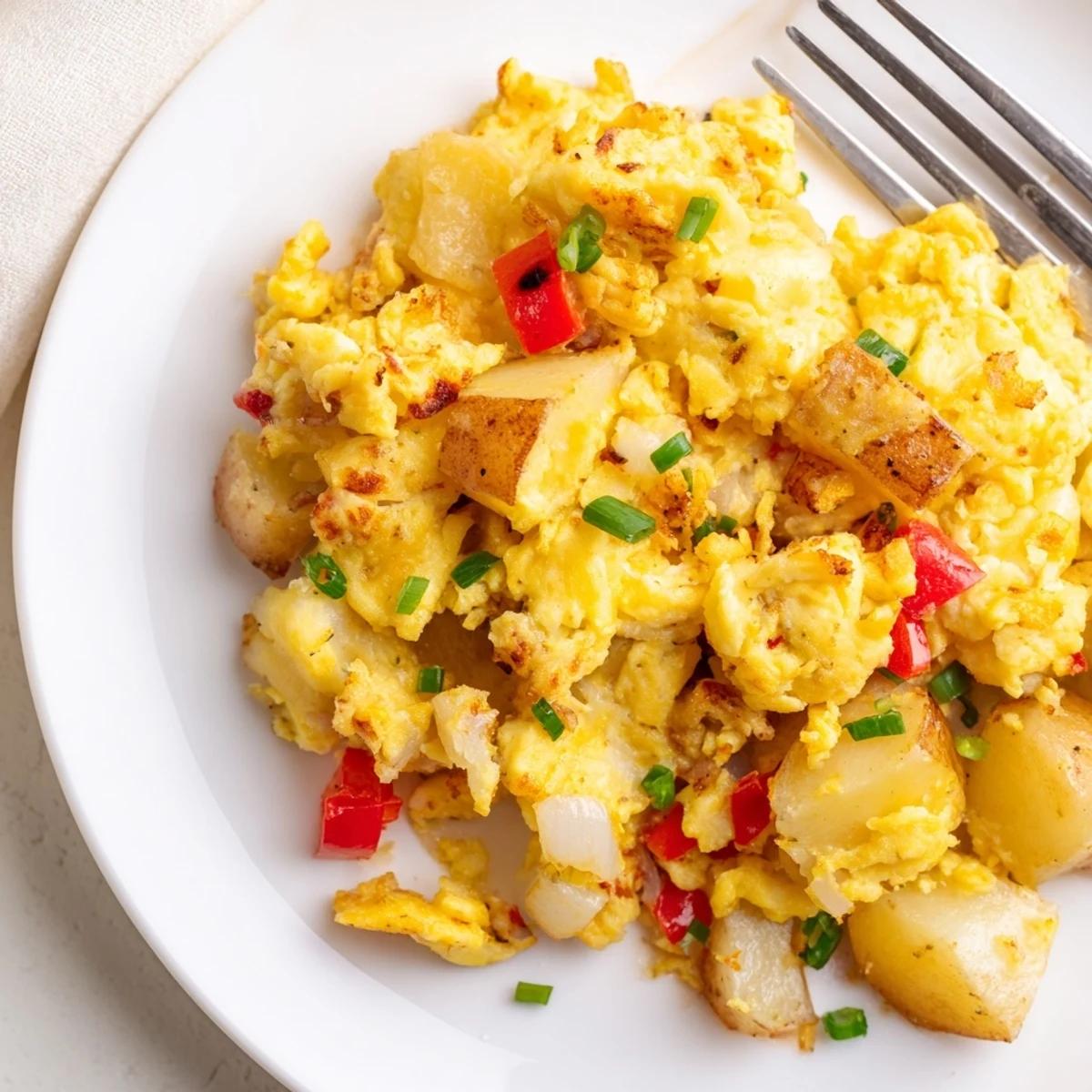 Golden brown potatoes and fluffy scrambled eggs with melted cheddar cheese in a skillet