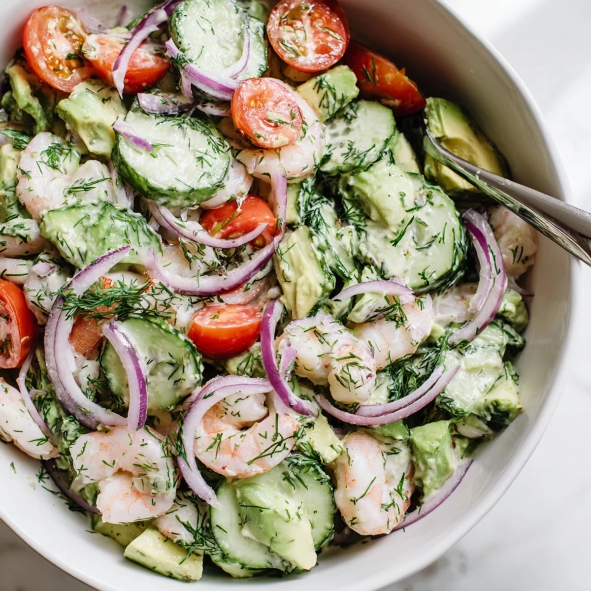 Light and refreshing cucumber shrimp salad featuring ripe avocado, cherry tomatoes, and red onion on a wooden table