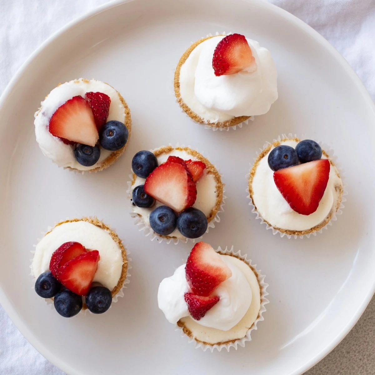 Creamy individual vanilla cheesecakes baked in muffin tins with crisp cookie bottoms and smooth tops