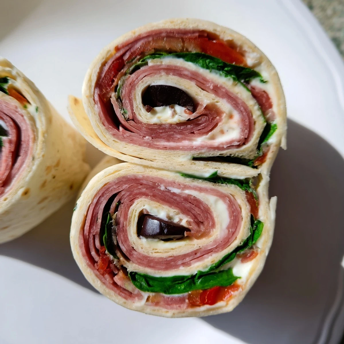 Italian Pinwheel Sandwiches sliced into spirals revealing layers of salami pepperoni ham provolone and roasted red peppers