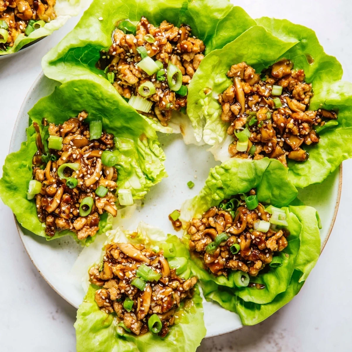 Easy chicken lettuce wraps garnished with green onions and sesame seeds for a light appetizer