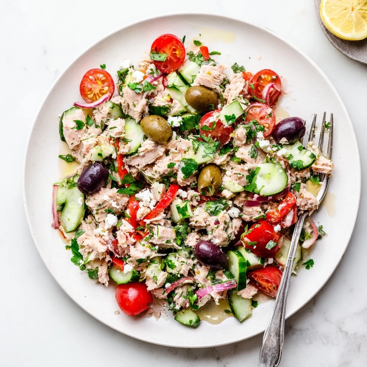 Zesty Mediterranean tuna salad topped with crumbled feta and crisp vegetables in a white bowl.