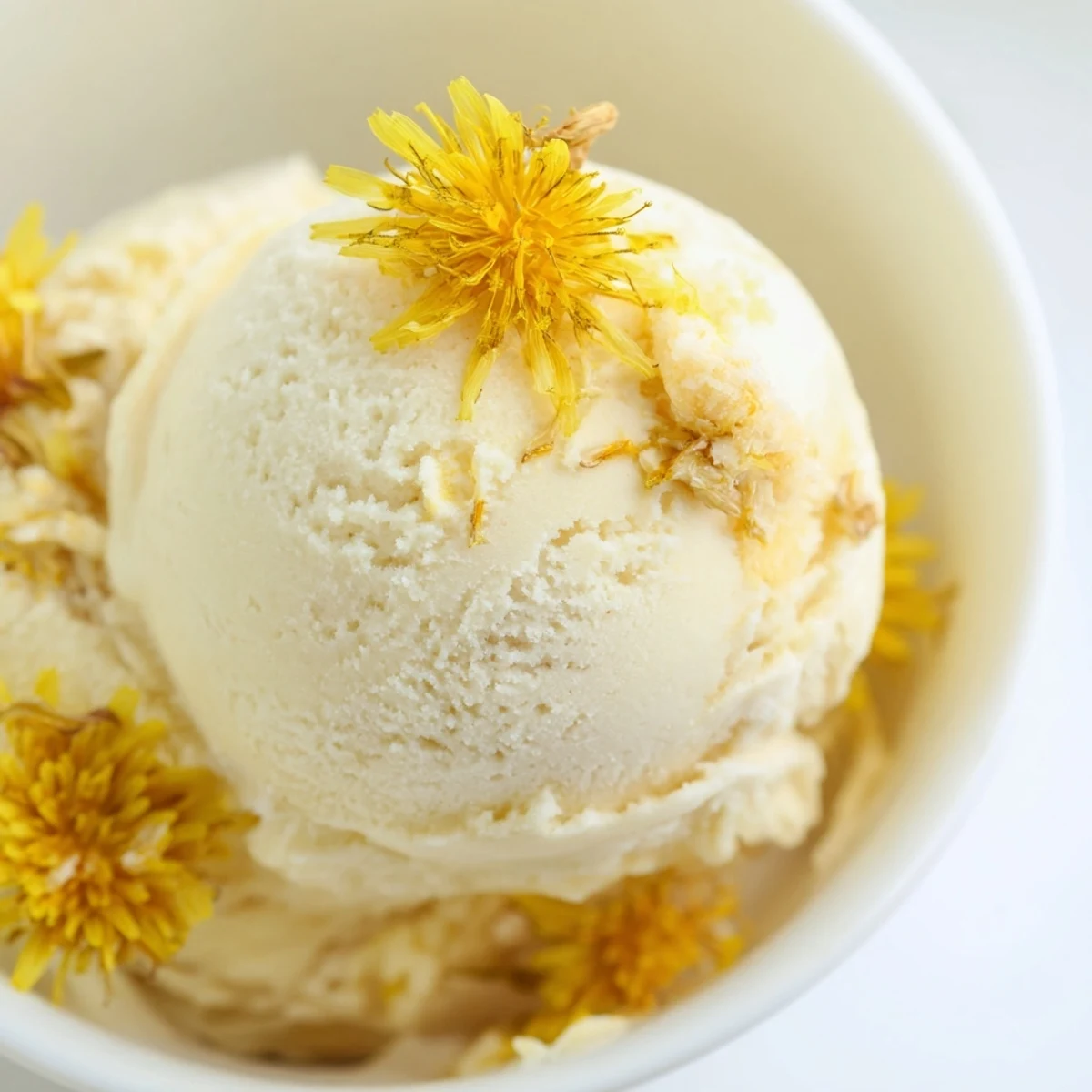 Velvety homemade dandelion honey ice cream drizzled with extra honey on a summer day
