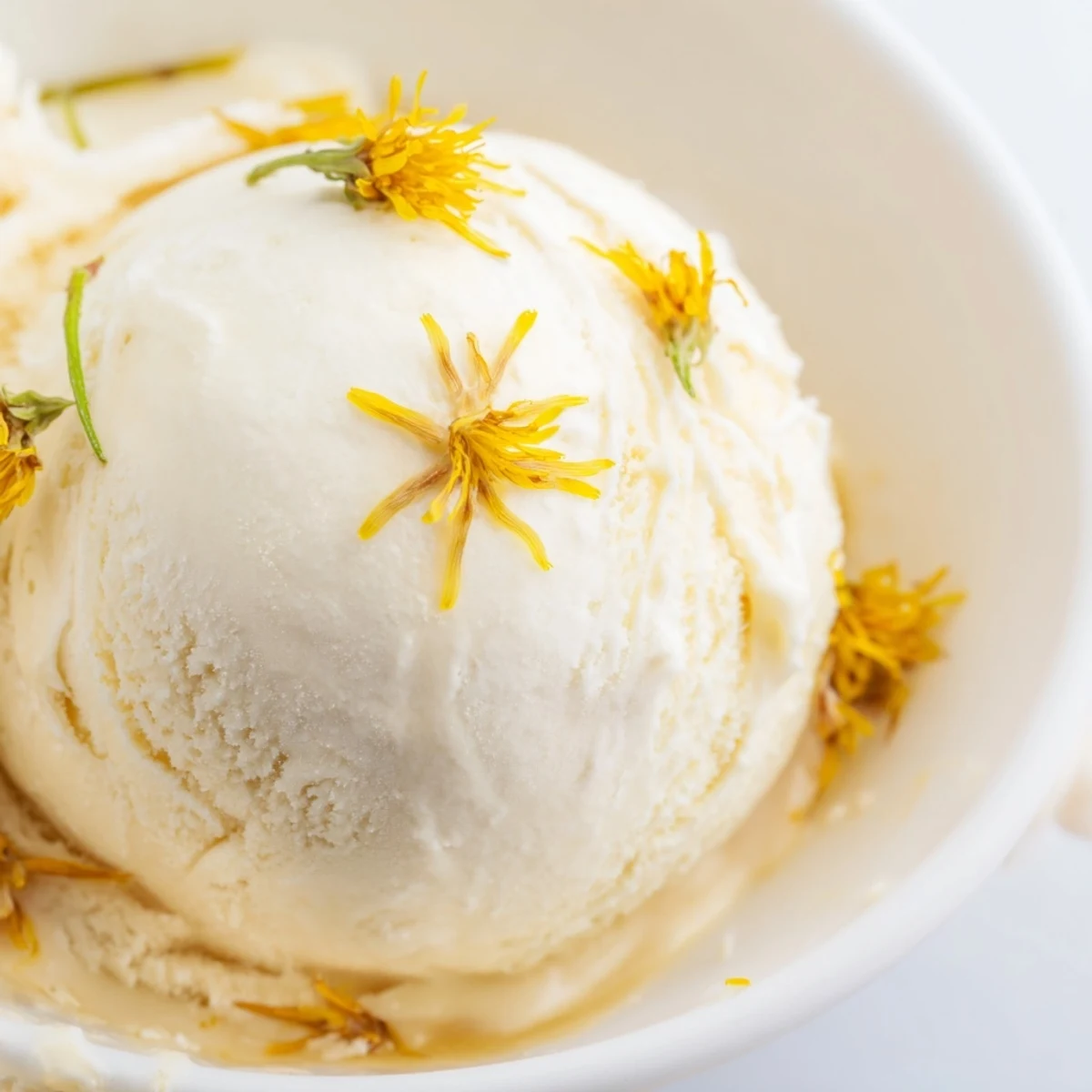 Golden floral dandelion honey ice cream served with fresh dandelion petals and shortbread cookies