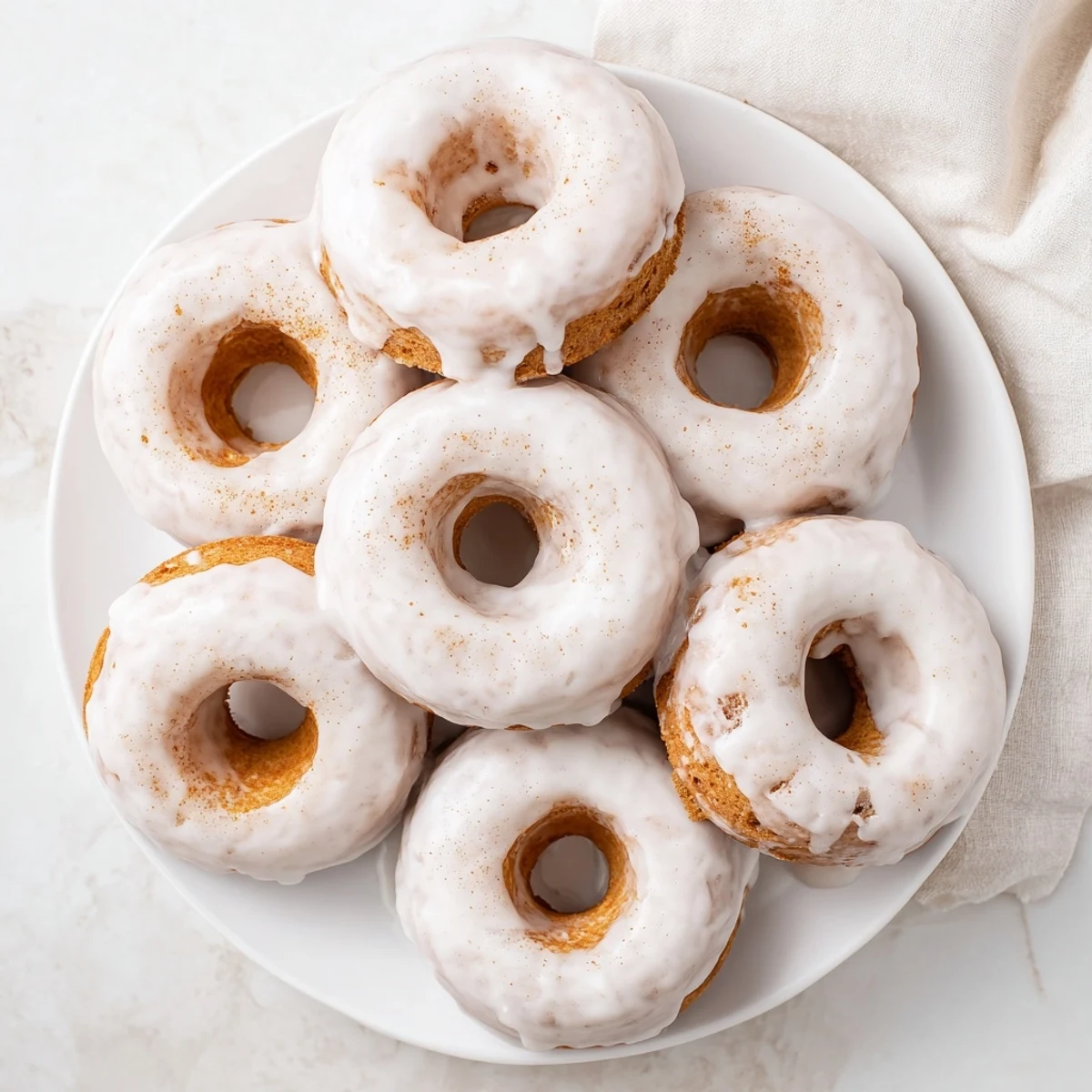 Baked Greek yogurt cake donuts arranged on a serving plate with powdered sugar dusting