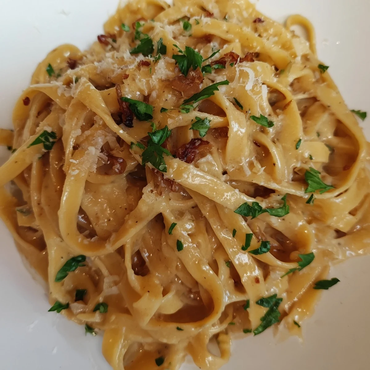 Sweet Heat Caramelized Onion Fettuccine in a creamy sauce topped with red chili flakes and Parmesan cheese