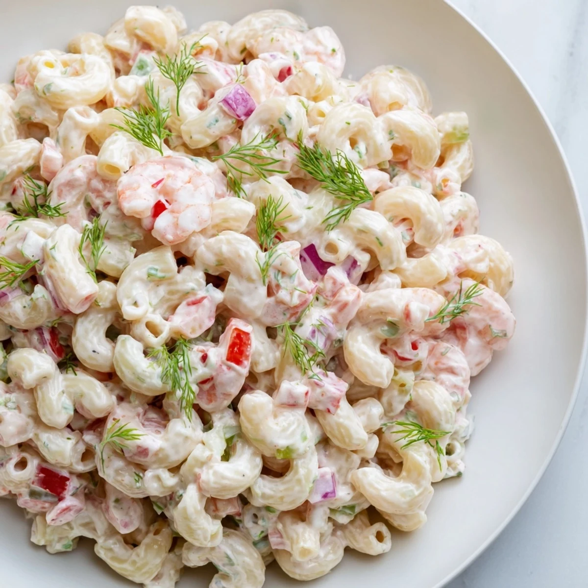 Creamy shrimp macaroni salad topped with fresh herbs in a rustic serving bowl