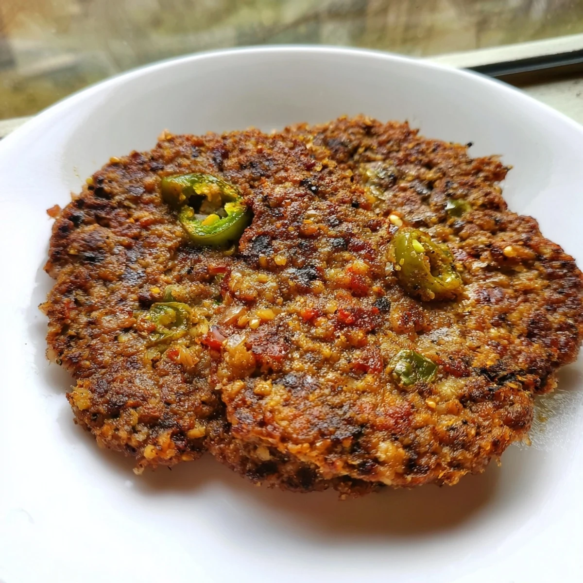 Spiced Pakistani Chapli Kabab served with fresh naan bread cool mint yogurt raita