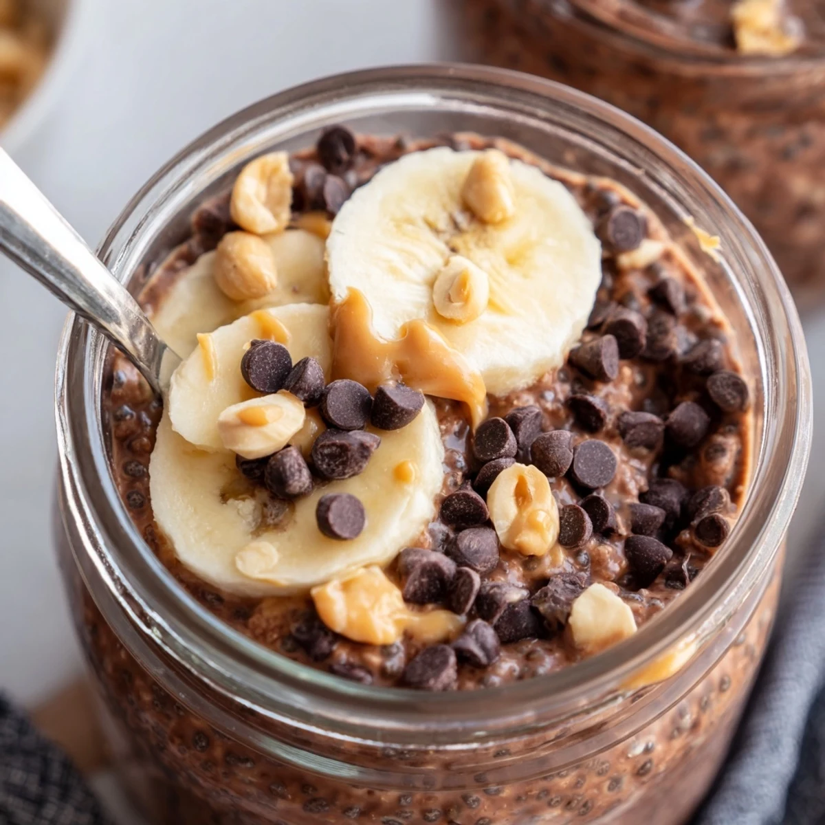 Thick chocolate peanut butter overnight oats served in a mason jar with sliced banana toppings