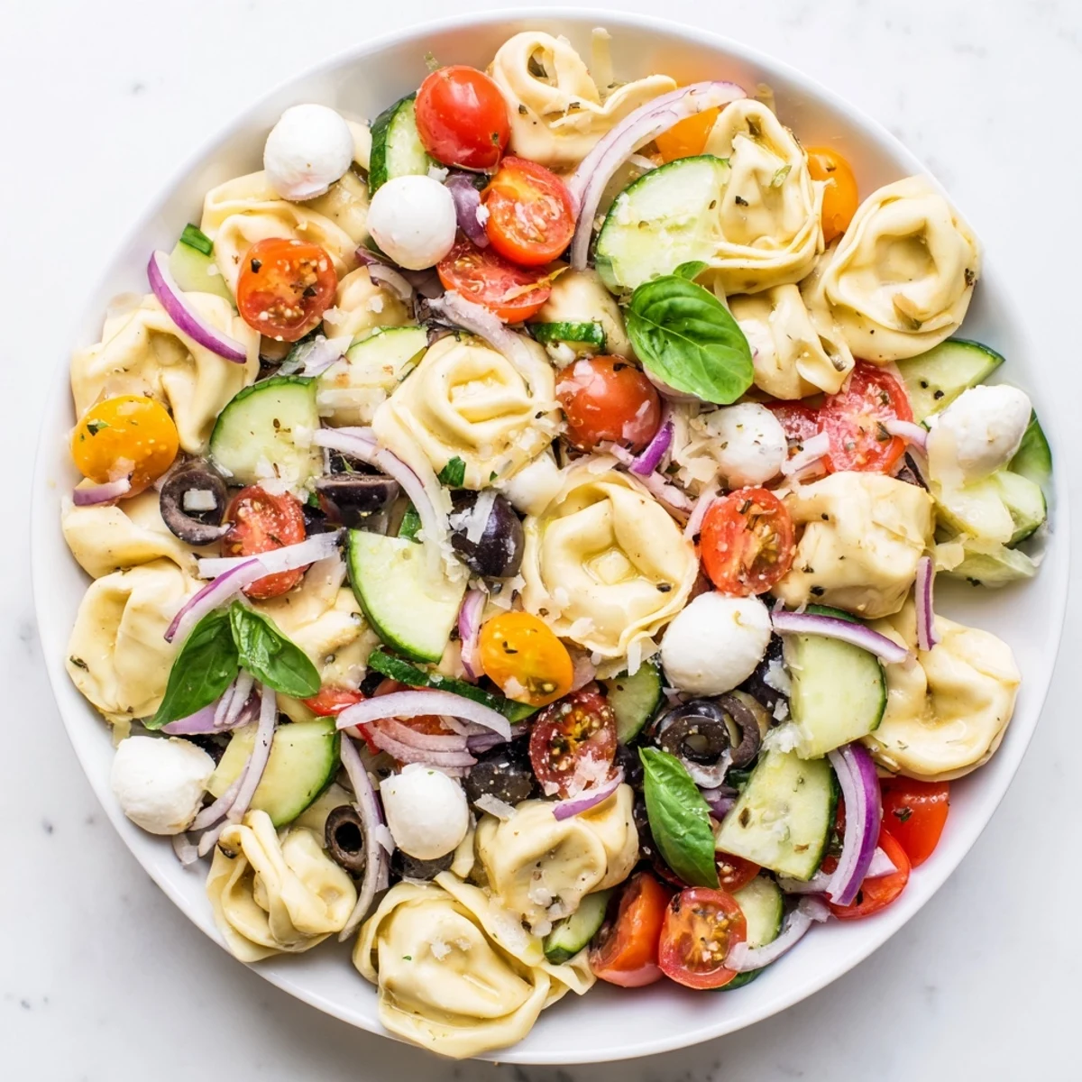 Colorful tortellini salad with cherry tomatoes, cucumber, and mozzarella in Italian dressing