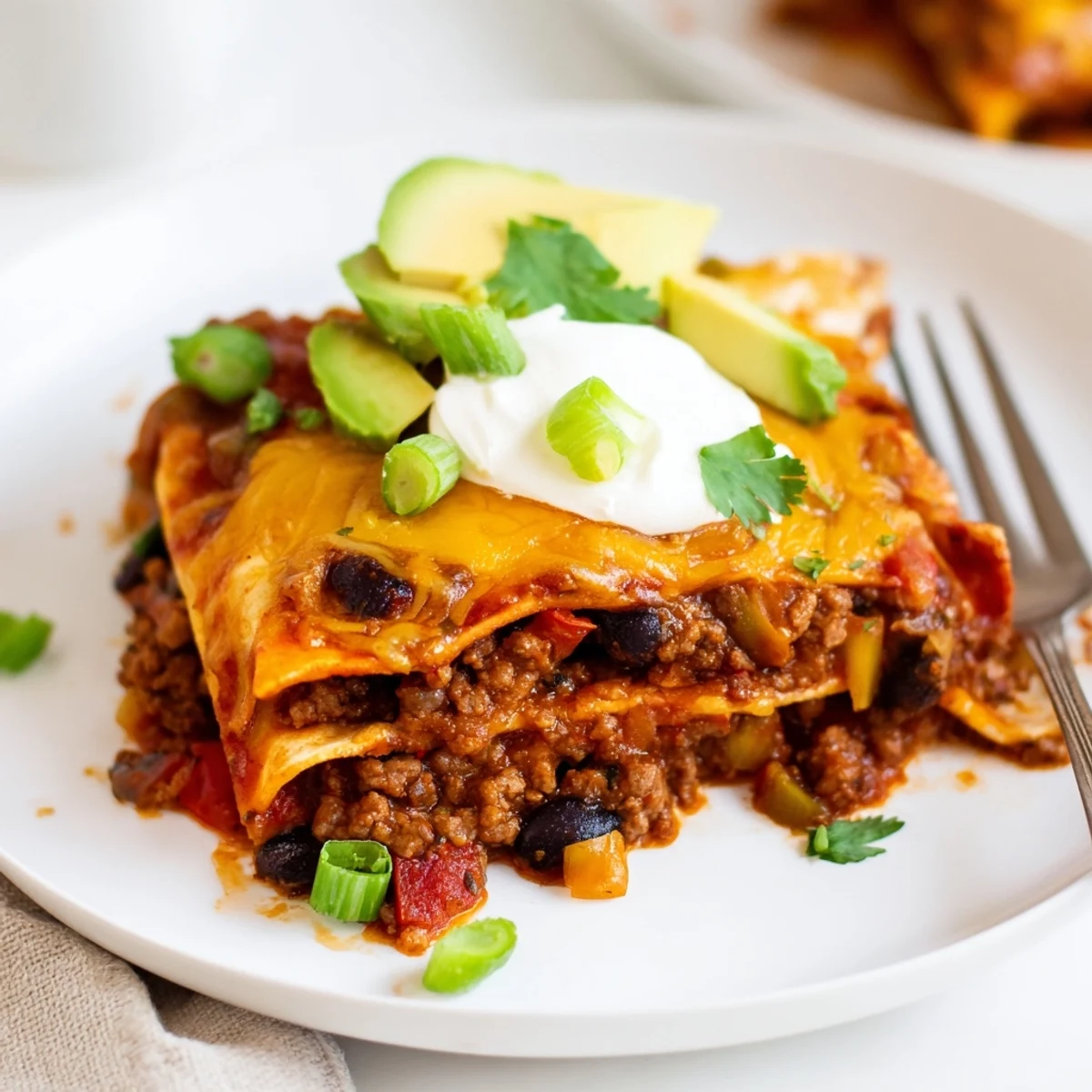Beef Skillet Enchiladas topped with avocado, green onions, and creamy sour cream