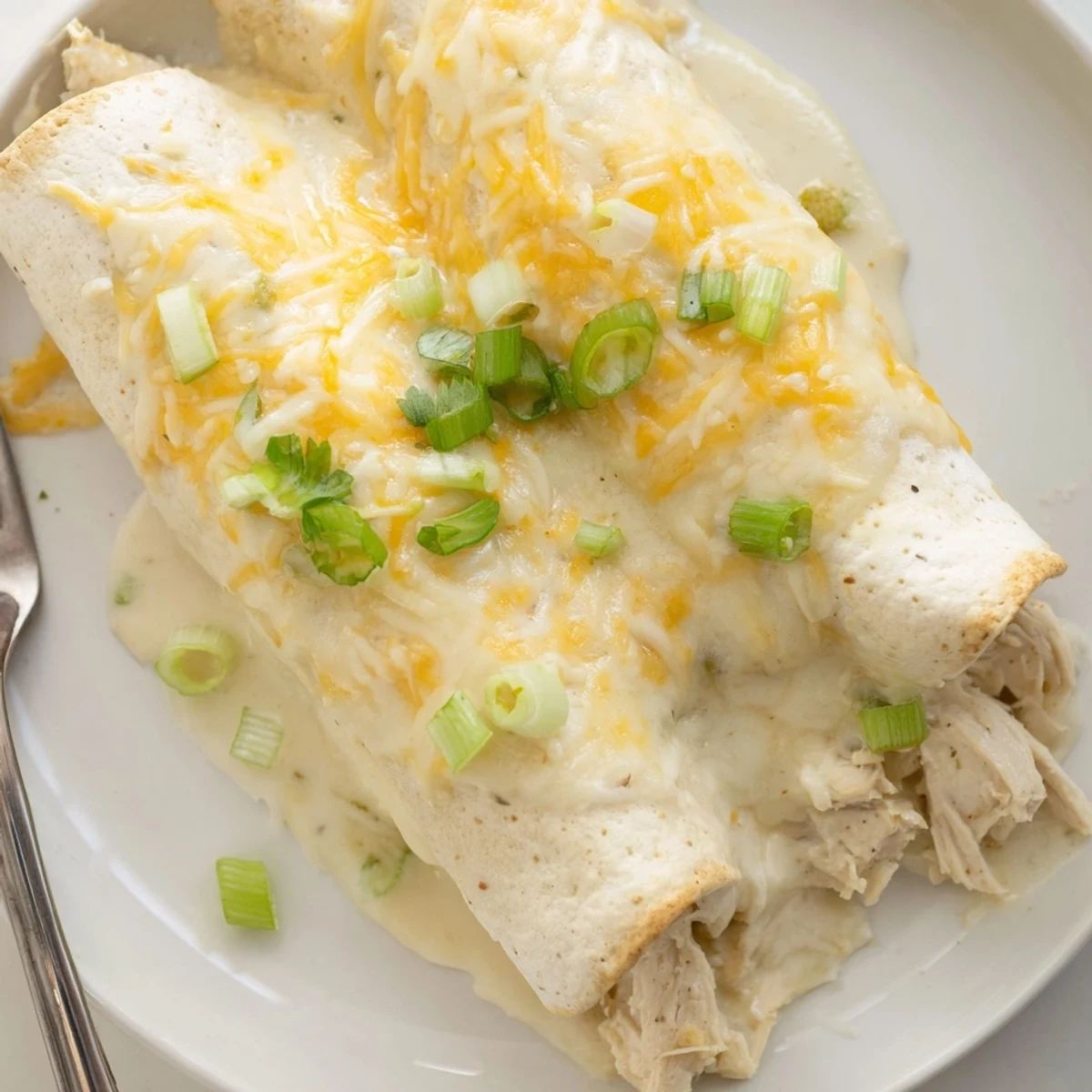 Creamy White Chicken Enchiladas bubbling golden, garnished with cilantro and green onions