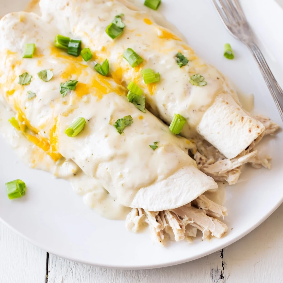 A close-up of Creamy White Chicken Enchiladas, velvety sauce pooling, ready to serve