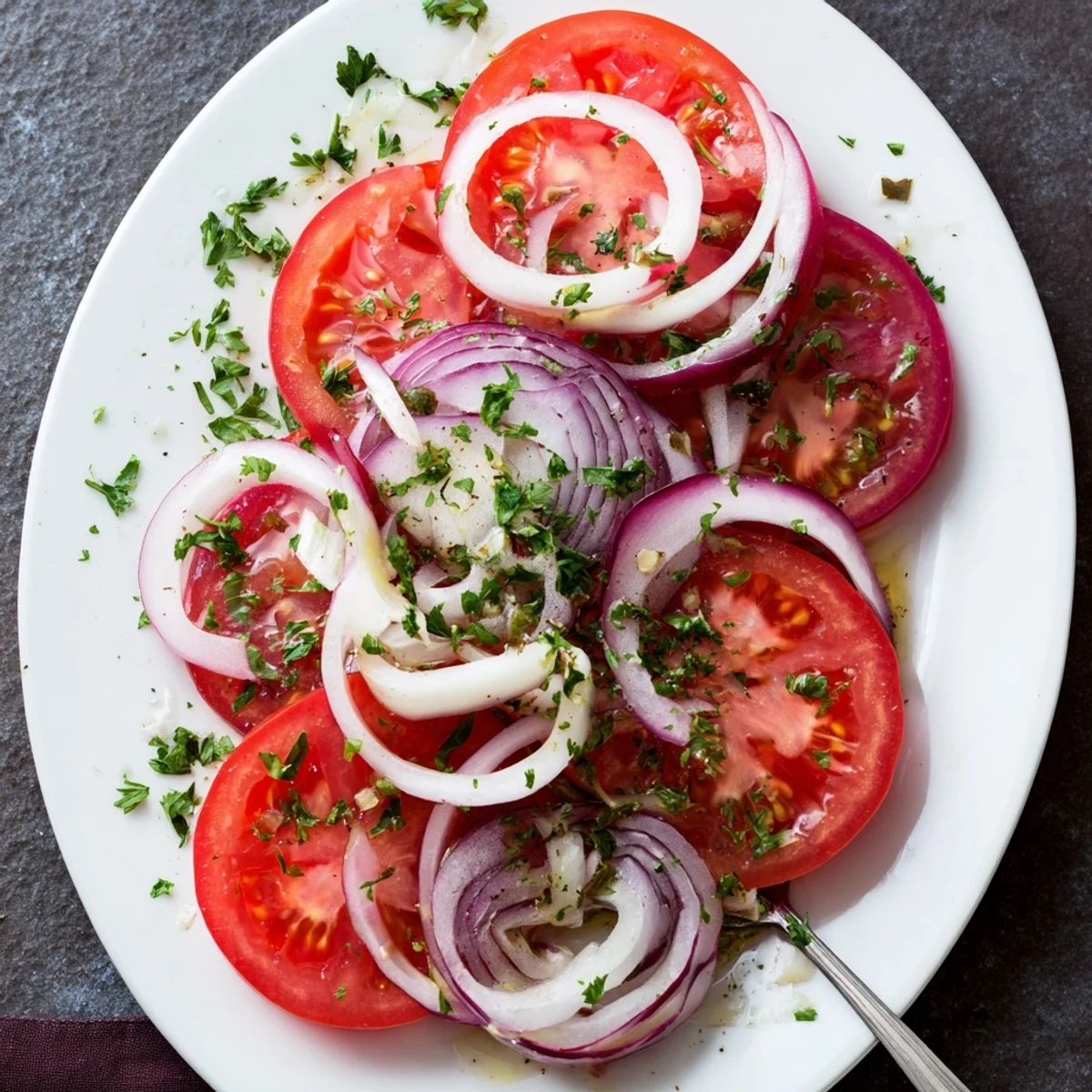 Mediterranean-style tomato and onion salad marinated in tangy vinaigrette, featuring crisp red onion rings and juicy tomato slices