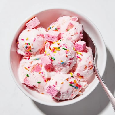 Creamy No Churn Bubblegum Ice Cream topped with colorful sprinkles served in a clear dessert bowl.